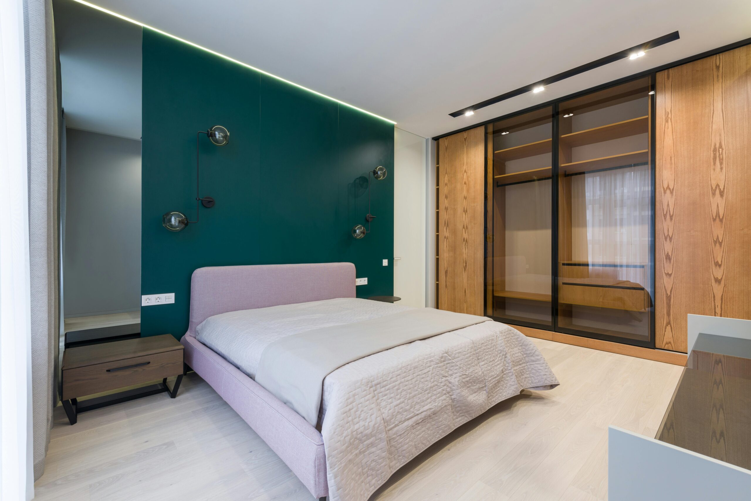 Interior of modern bedroom with comfortable bed with coverlet and big wardrobe with wooden and glass sliding doors